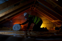 Worker installing insulation in an attic ,UK stainable energy.