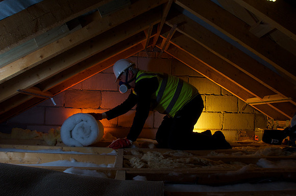 Worker installing insulation in an attic ,UK stainable energy.