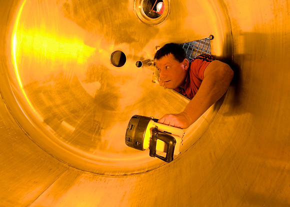 Brewery technician inspects a tank.